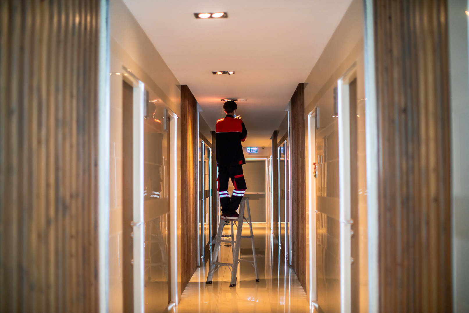 Technician is replacing or repair a smoke detector in an office building or condominium.  Technician is checking a fire alarm system at smoke detector. Building support.